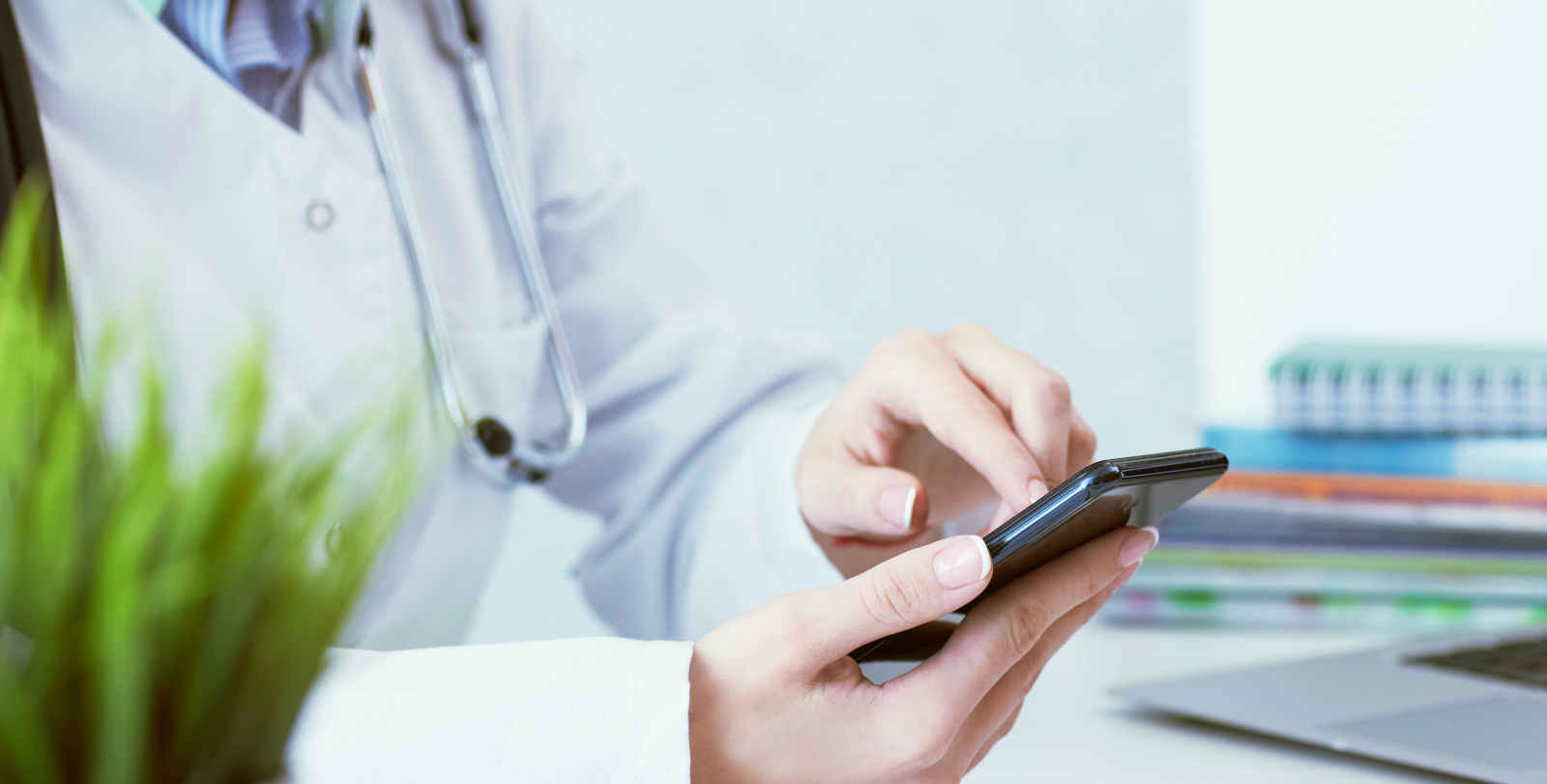 Soft focus of woman doctor touching screen on modern smart phone during the consultation in the workplace hospital.