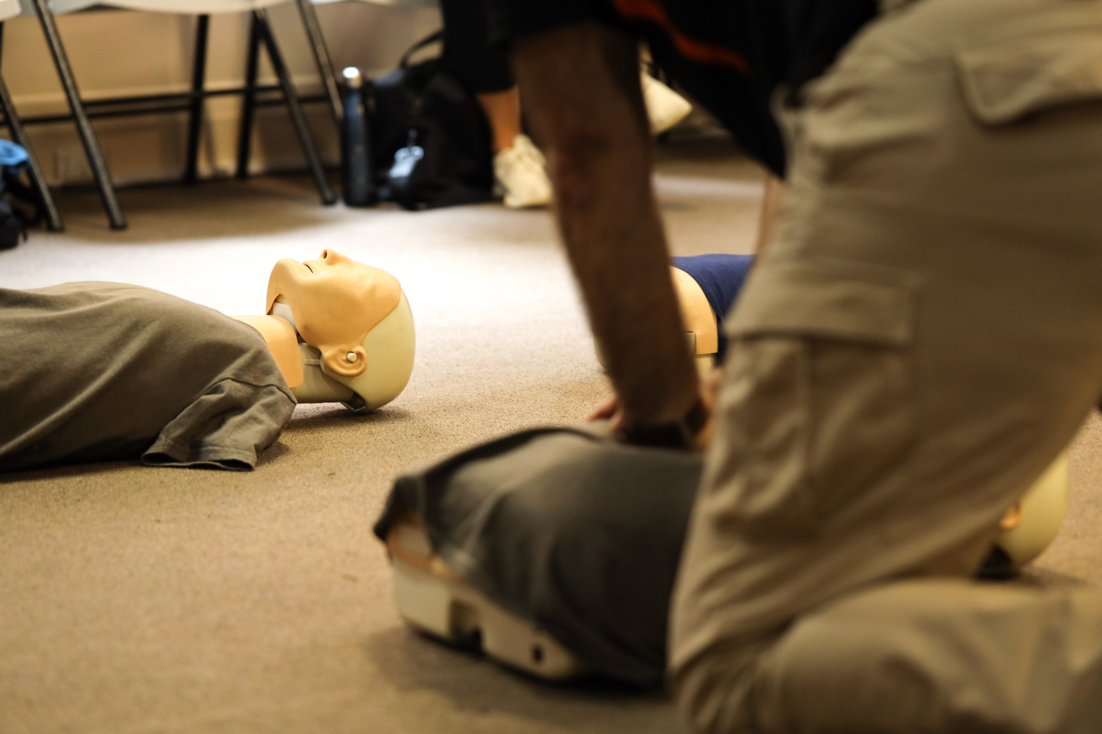 Defocused of instructor hand demonstration performing CPR on adu