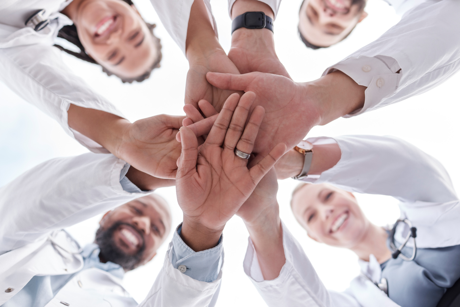 Hospital doctors, happy people and circle hands together for healthcare teamwork, medical team building and clinic celebration. Solidarity, below view and group surgeon for collaboration success Healthcare staff team working concept using YouRecruit