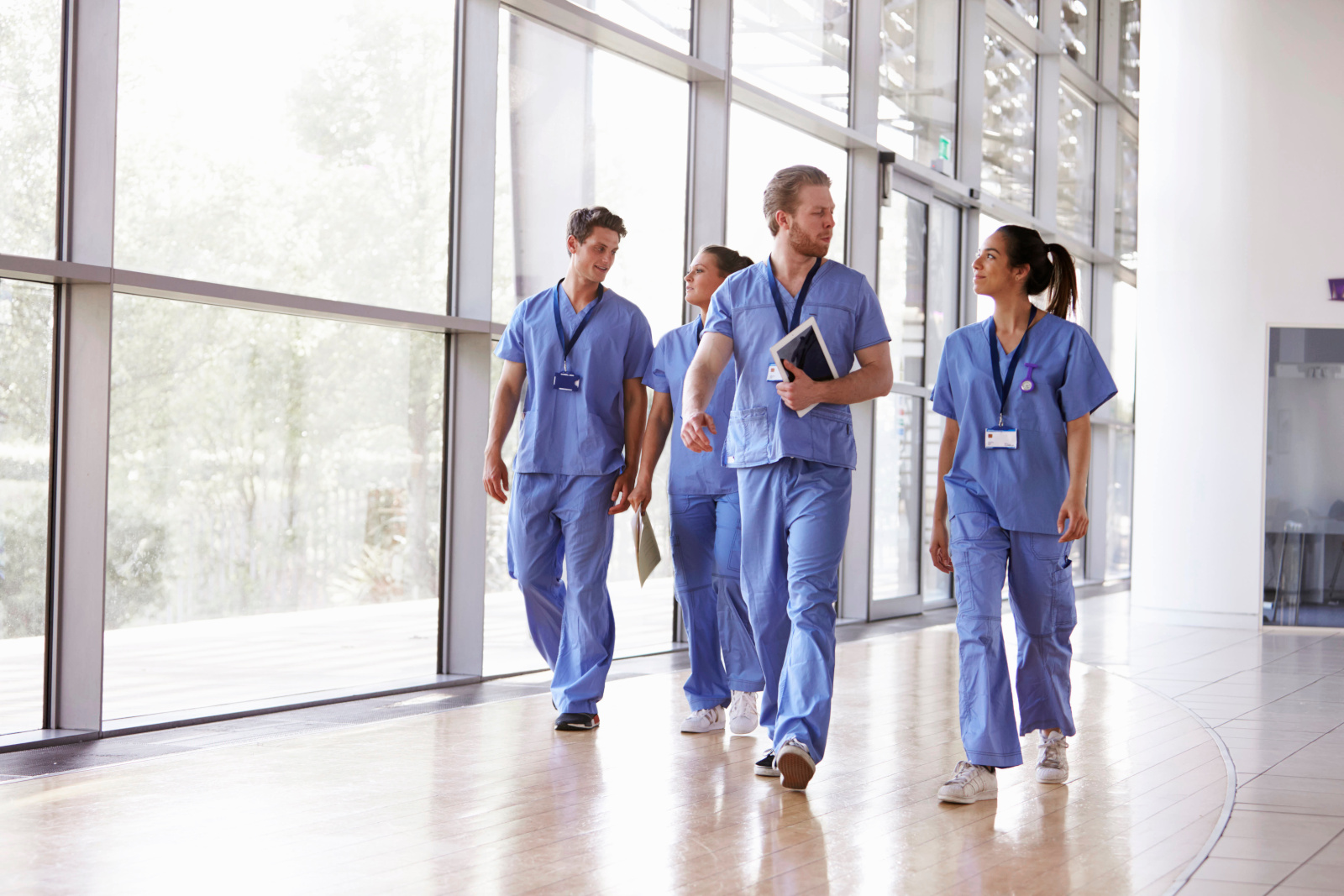 Four healthcare workers in scrubs walking in corridor Healthcare team on the move using the WorkTracker branded app