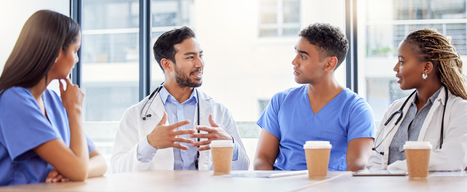 Four medical staff in breakroom having coffee