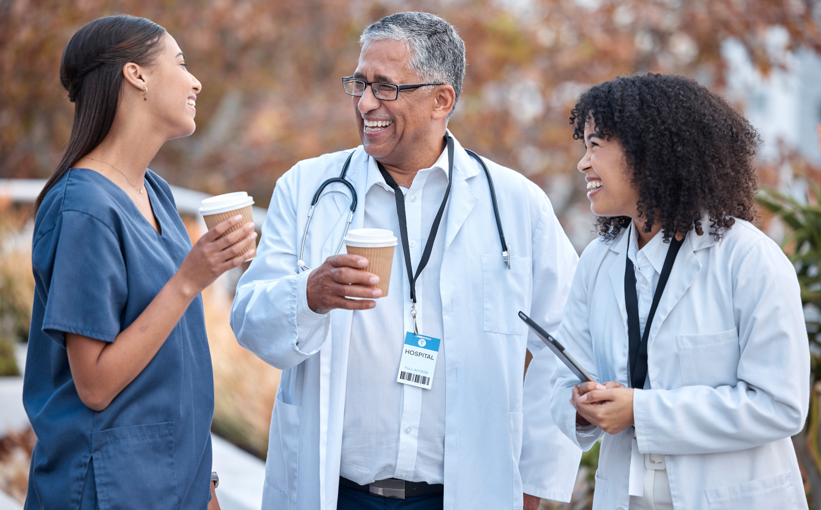 Coffee break, talking and doctors for healthcare planning, happy conversation and outdoor advice from mentor. Internship, funny and social life of medical women, nurses and clinic staff with drink Nurse and two doctors having outdoor coffee break
