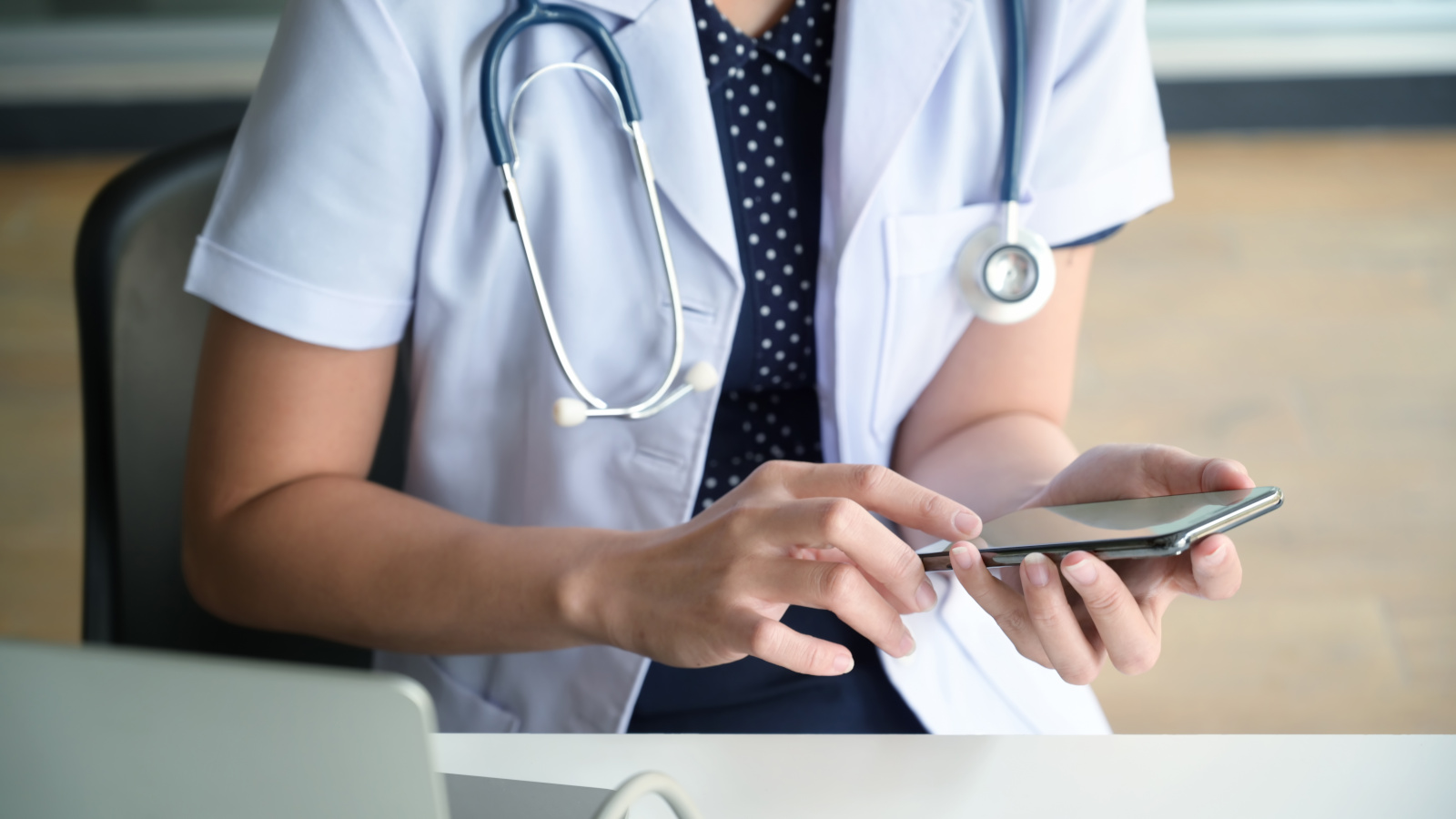 Cropped image of female doctor texting and using on smartphone Temporary employee doctor at desk with smartphone checking her schedule using the WorkTracker workshift appointments app