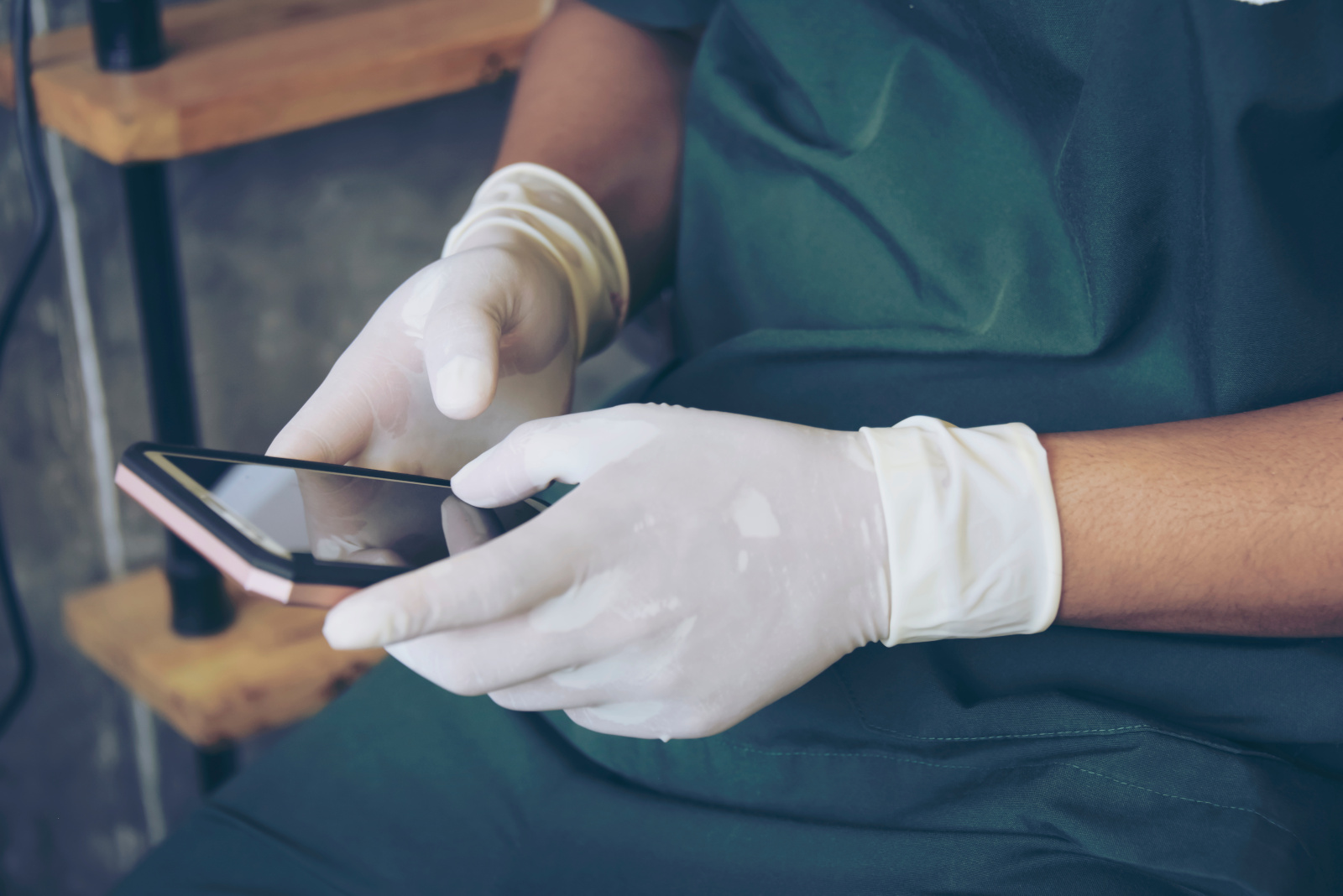 Two Doctor in green surgical gown hand working with smart phone. Medical technology network team meeting concept The YouRecruit branded WorkTracker timesheet app