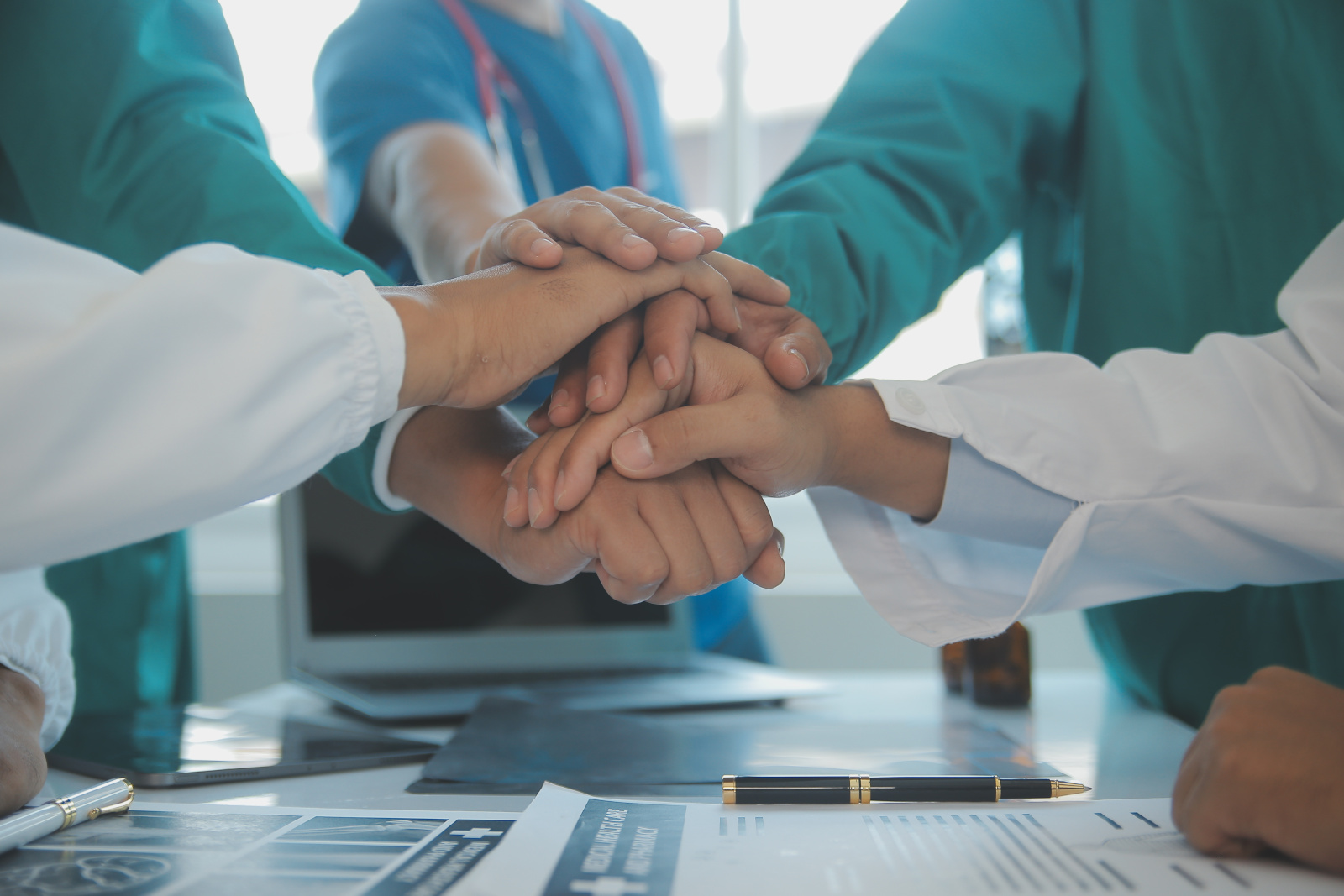 Doctors and nurses in a medical team stacking hands YouRecruit team working concept