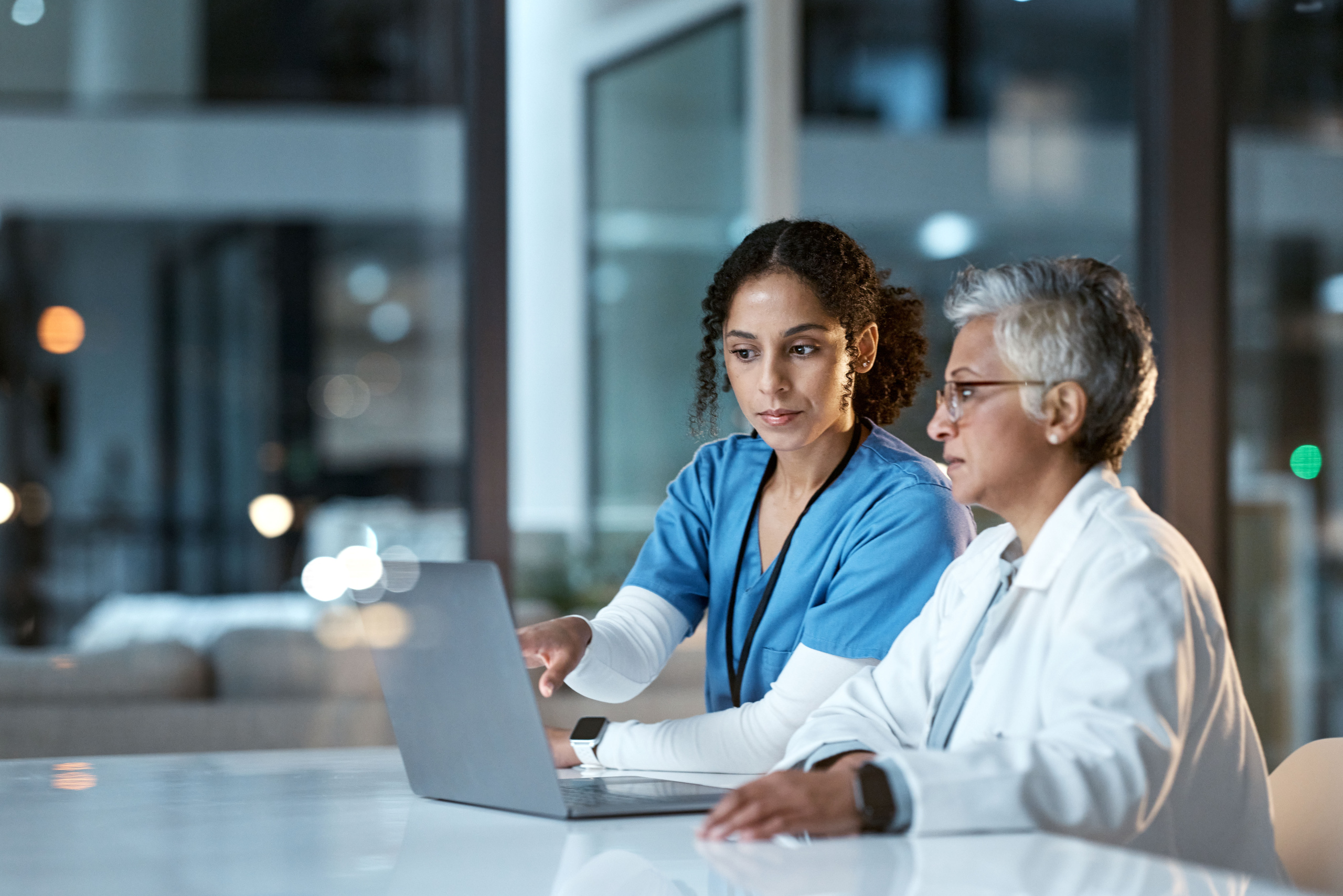 Team of doctors, health and women with laptop, work together and digital clinic schedule or agenda. Technology, medical innovation and healthcare collaboration, partnership and cardiovascular surgeon Two healthcare managers at laptop discussing hospital shift scheduling: YouRecruit employee availability management