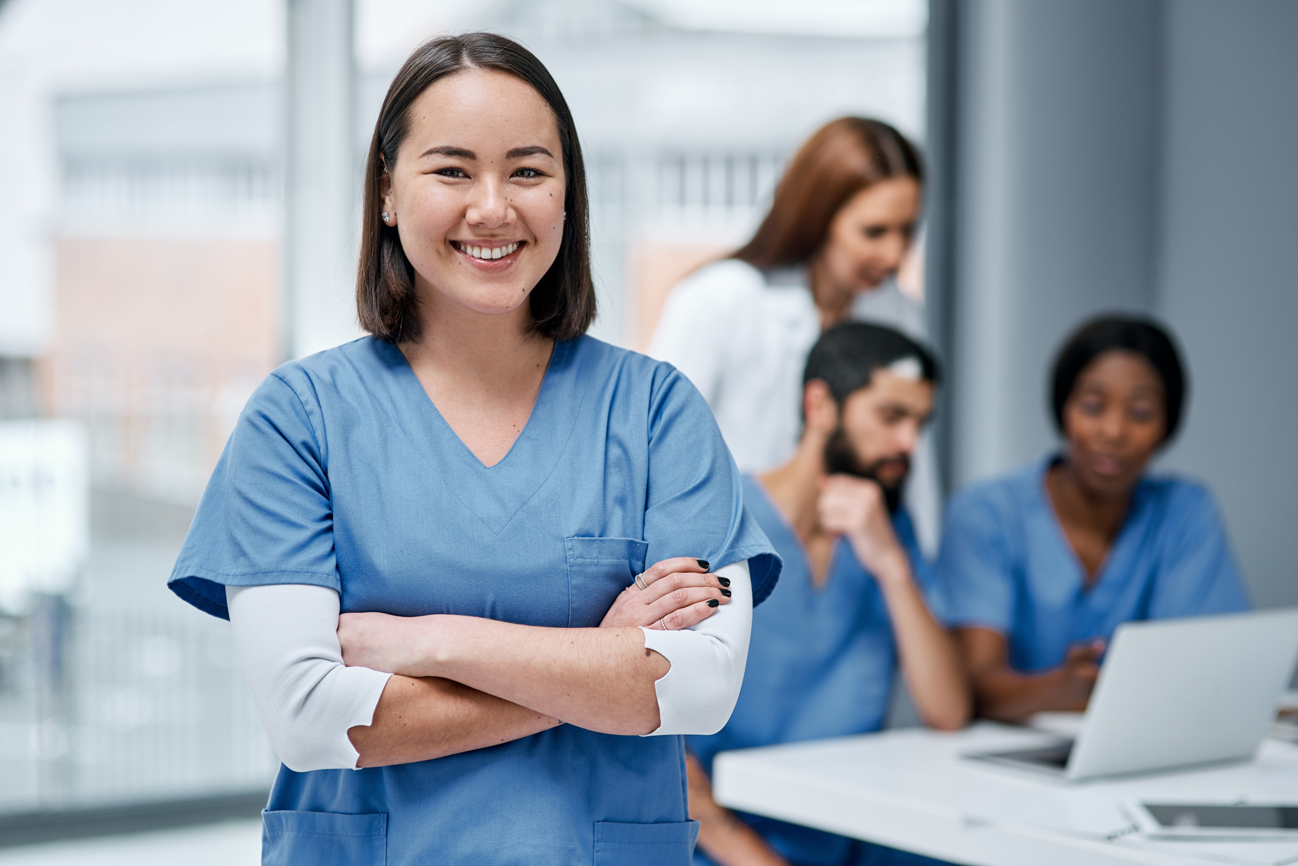 Happy temporary doctor with workforce scheduling team in the background: YouRecruit employee availability management