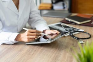 Cropped image of temporary employee doctor at desk with smart device: YouRecruit and the WorkTracker job hours app