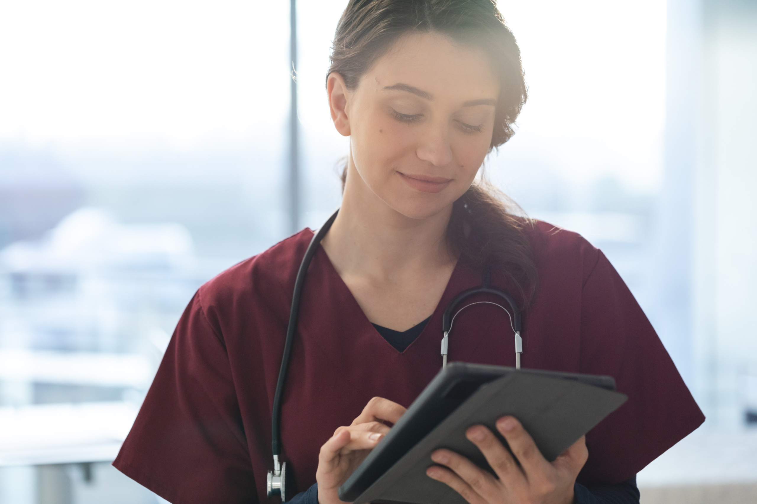 env-yr-happy-caucasian-female-doctor-wearing-scrubs-and-s-2025-04-04-11-24-02-utc2 Female doctor in scrubs using tablet for timesheet details: YouRecruit and the WorkTracker mobile workforce management app