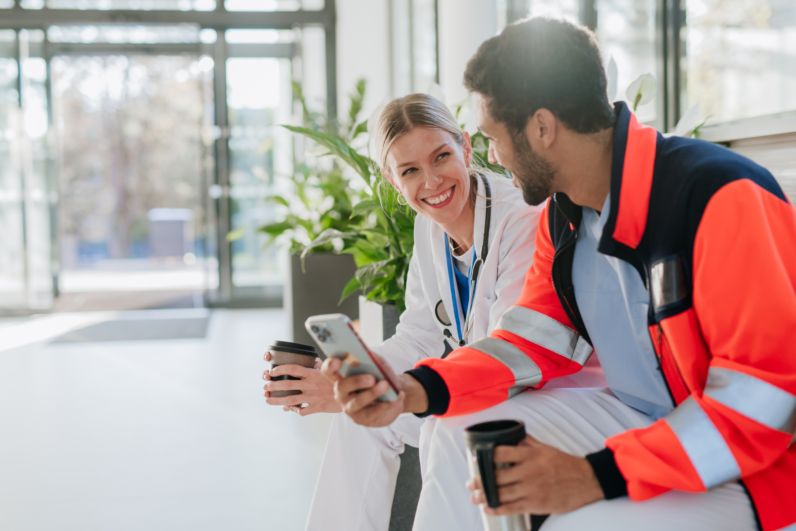 env-yr-rescuer-having-break-and-talking-with-doctor-colle-2024-10-18-15-29-13-utc2 Happy female doctor with an ambulance crew worker holding smartphone: YouRecruit and WorkTracker staffing agency software