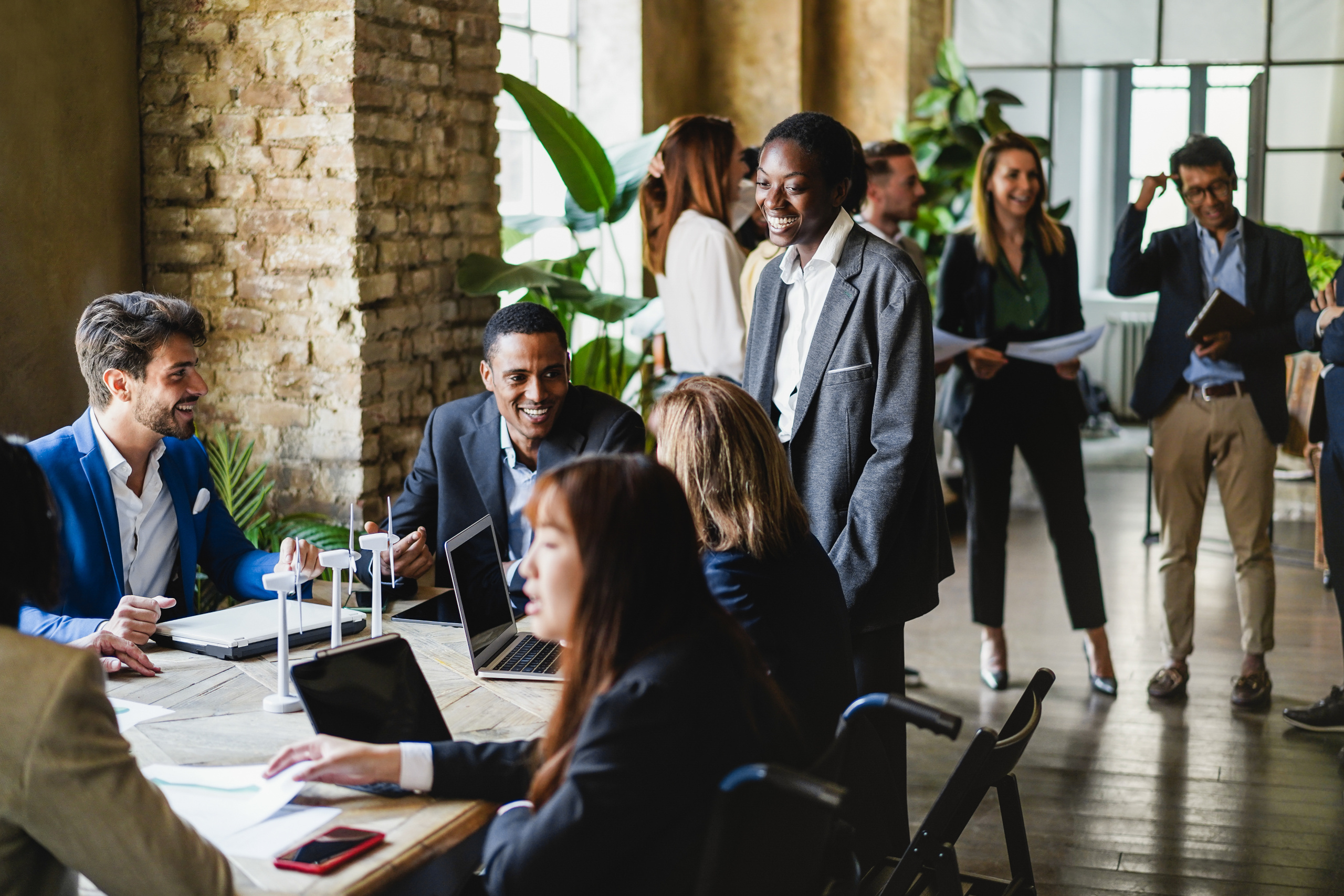 Group of relaxed recruitment agency consultants sat around desk with laptops: the YouRecruit temporary staffing software