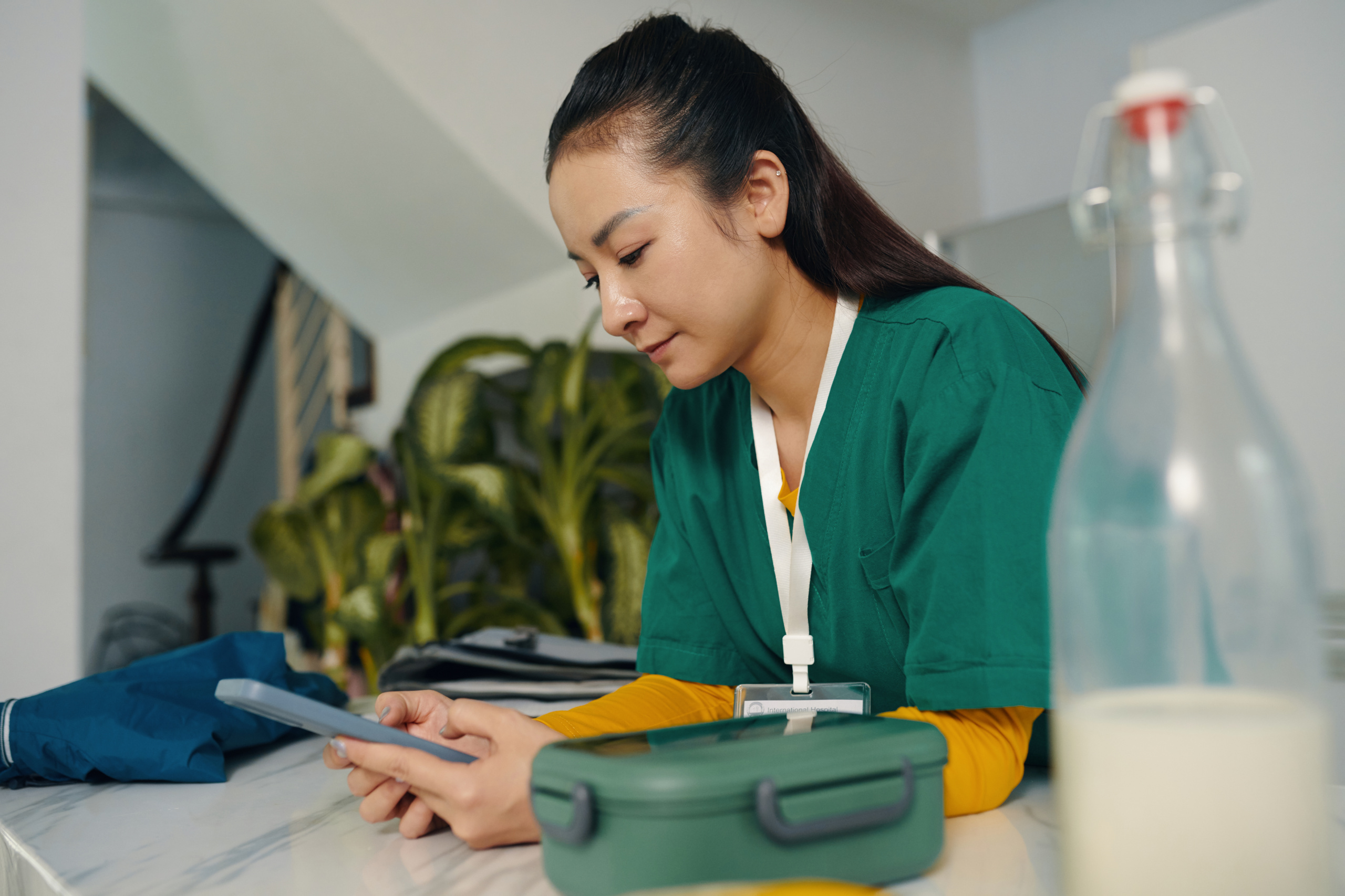 Asian nurse at work checking smart device and submitting timesheet: The WorkTracker mobile workforce management app