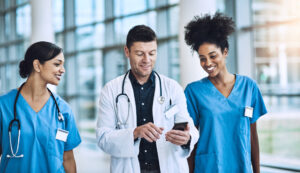 Two female nurses obtaining digital sign-off after completing a shift from male shift manager holding smart phone: YouRecruit
