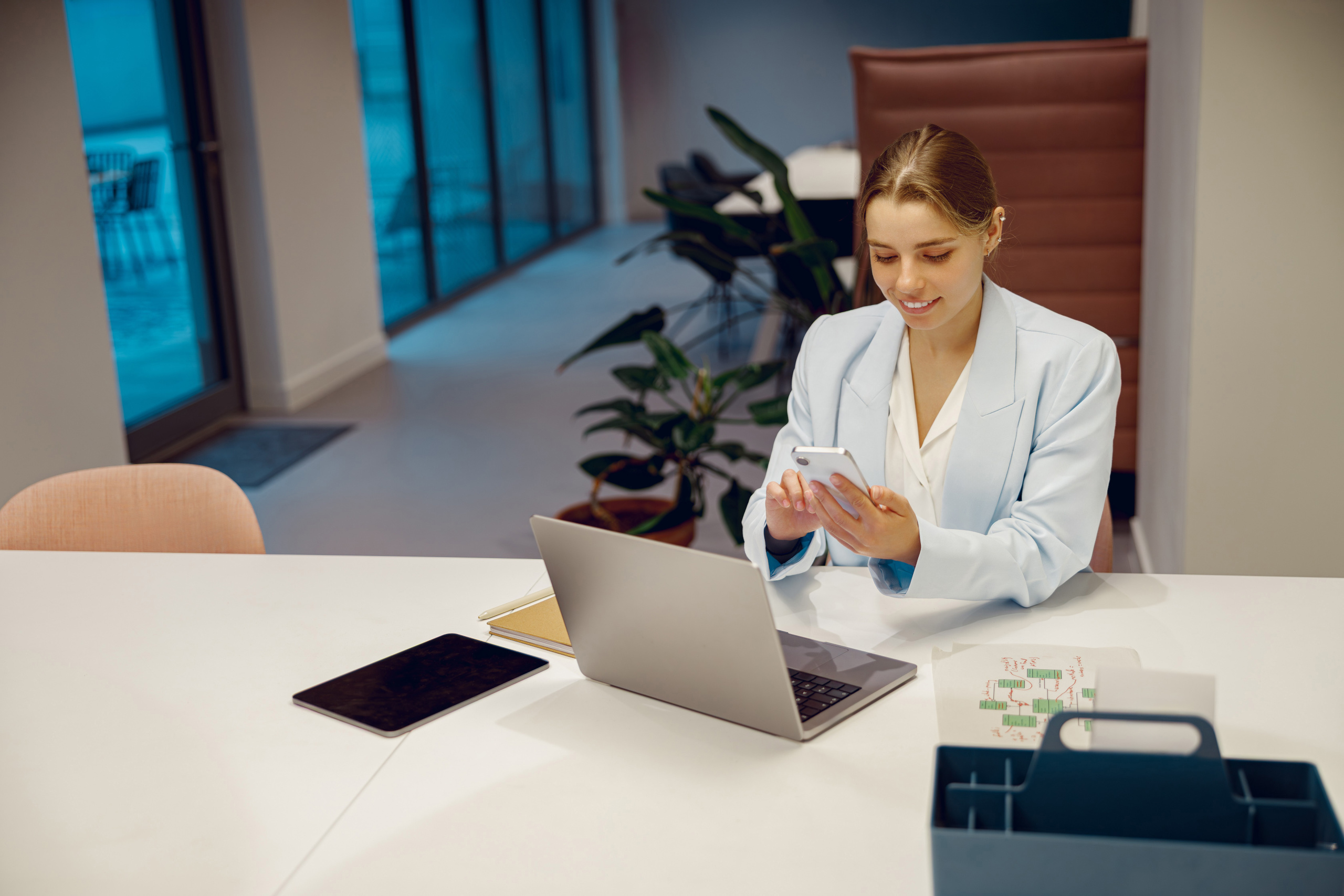 Recruitment consultant at desk with laptop and smart devices: The YouRecruit staff communication platform and timesheet app