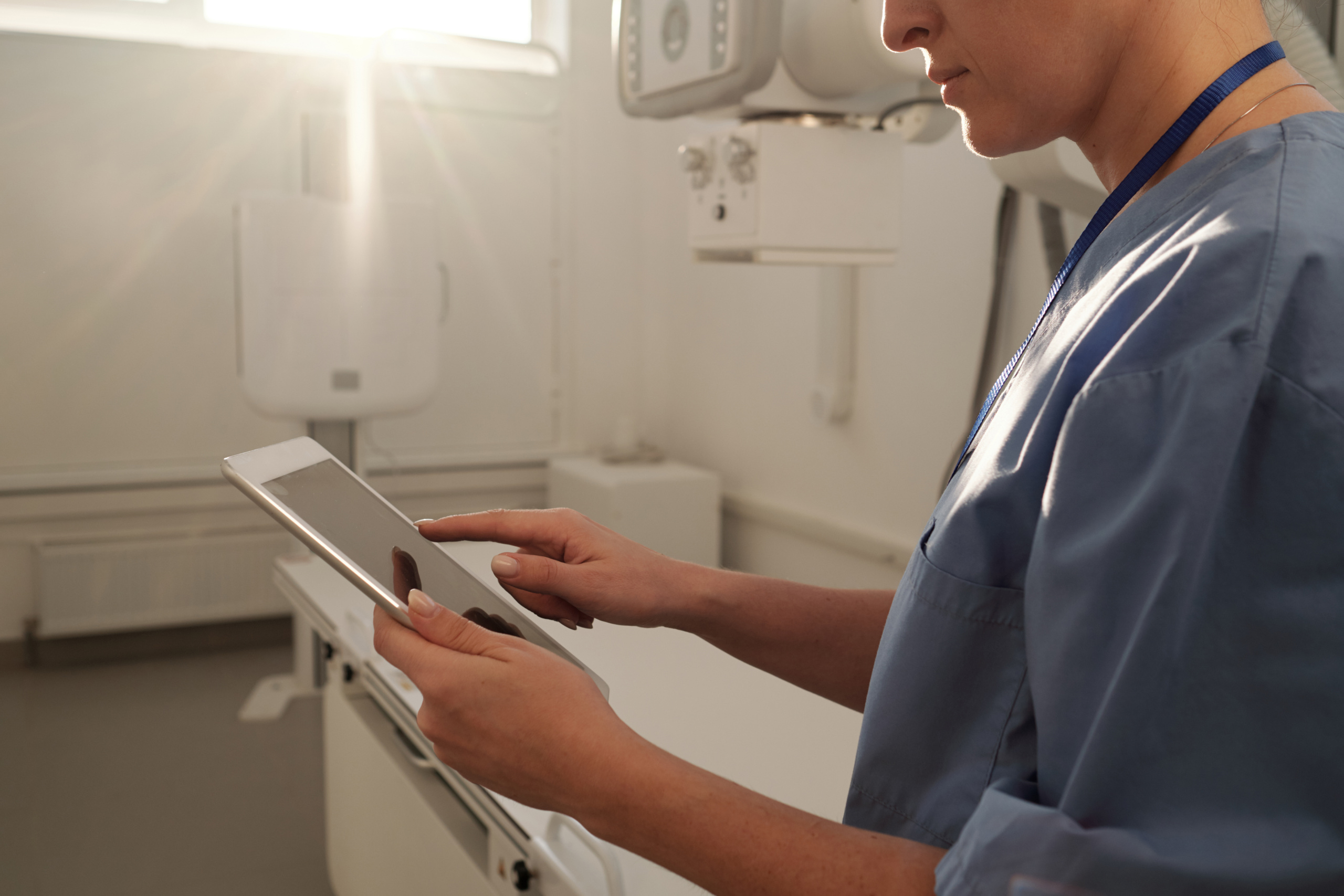 Healthcare professional within an operating theatre holding smart device: The YouRecruit staff communication platform