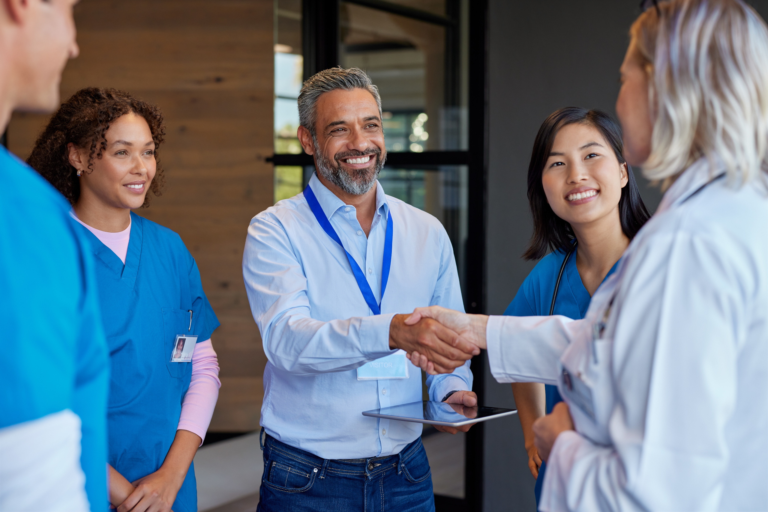 Hospital shift manager holding a tablet greets new staff working on location: Onboarding employees with YouRecruit