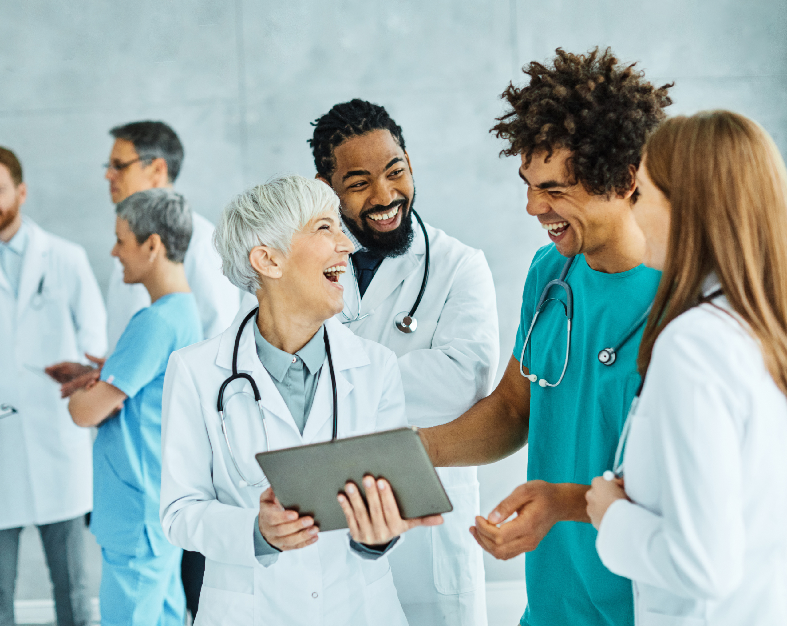 Group of happy temporary healthcare staff huddled around a tablet: YouRecruit and the WorkTracker mobile timesheet app