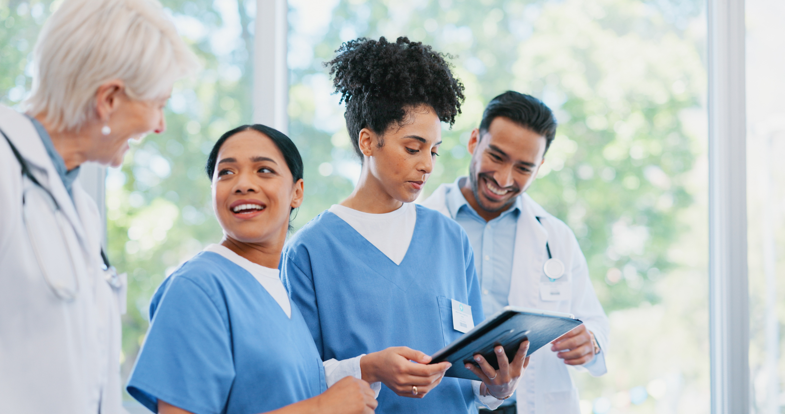 Group of happy male and female nurses, one checking the WorkTracker calendar on tablet: The WorkTracker Rota app