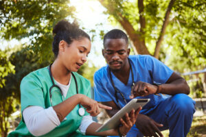 Two healthcare workers on a break in a park holding a tablet and checking the WorkTracker iOS and Android timesheet app