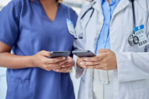 Two temporary healthcare employees holding smart phones checking the WorkTracker team scheduling app