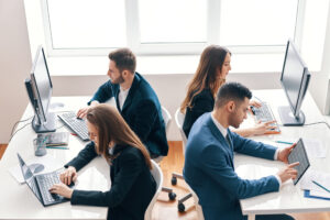 Four recruitment agency consultants in office with laptops: The YouRecruit staff communication platform