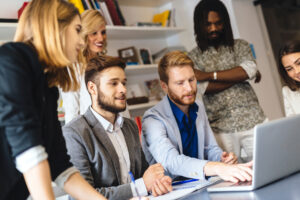 Recruitment agency consultants grouped around laptop training for managing temporary employee availability with YouRecruit