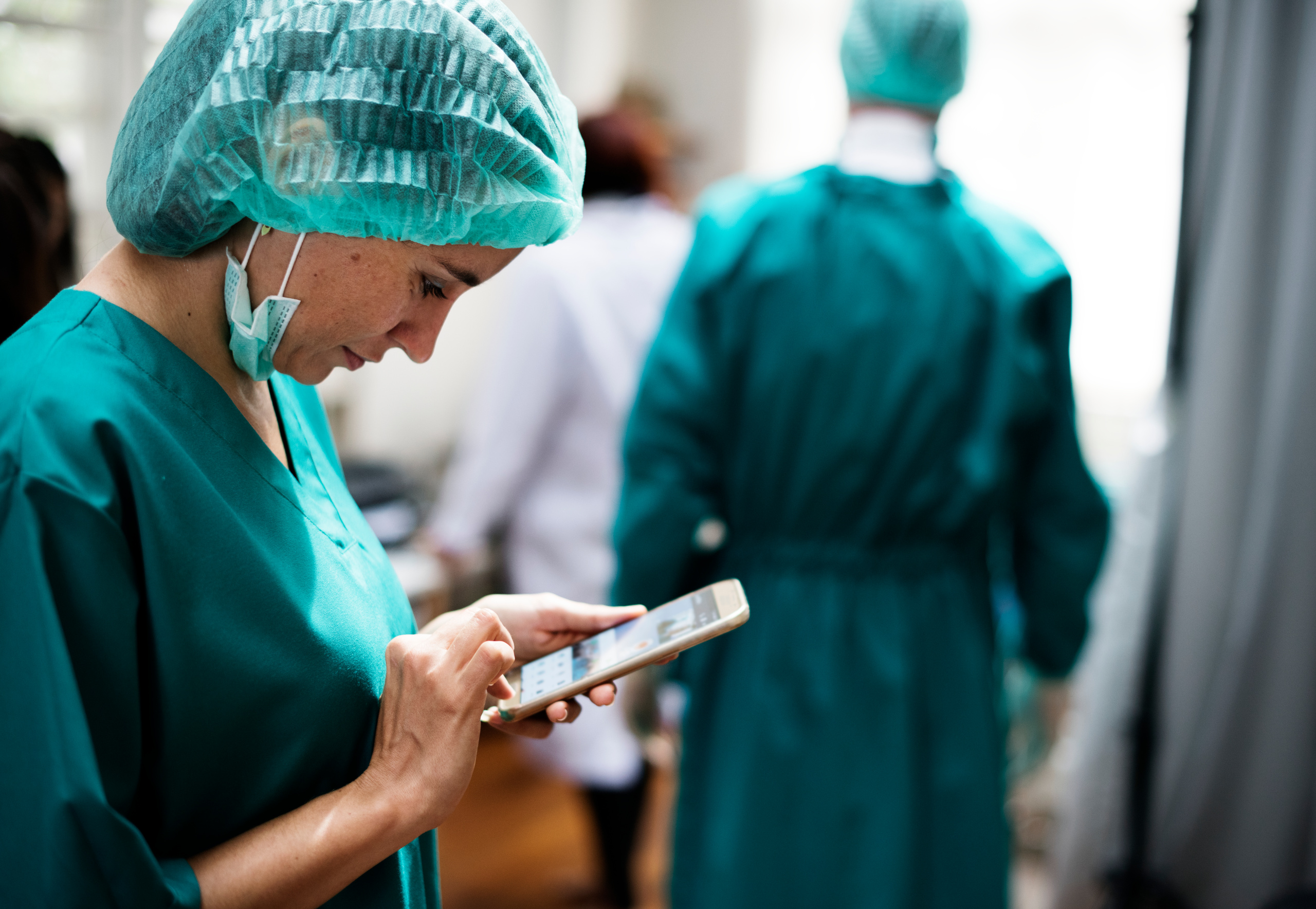 Nurse in scrubs with smart device and using the WorkerTracker mobile workforce management app for employee availability