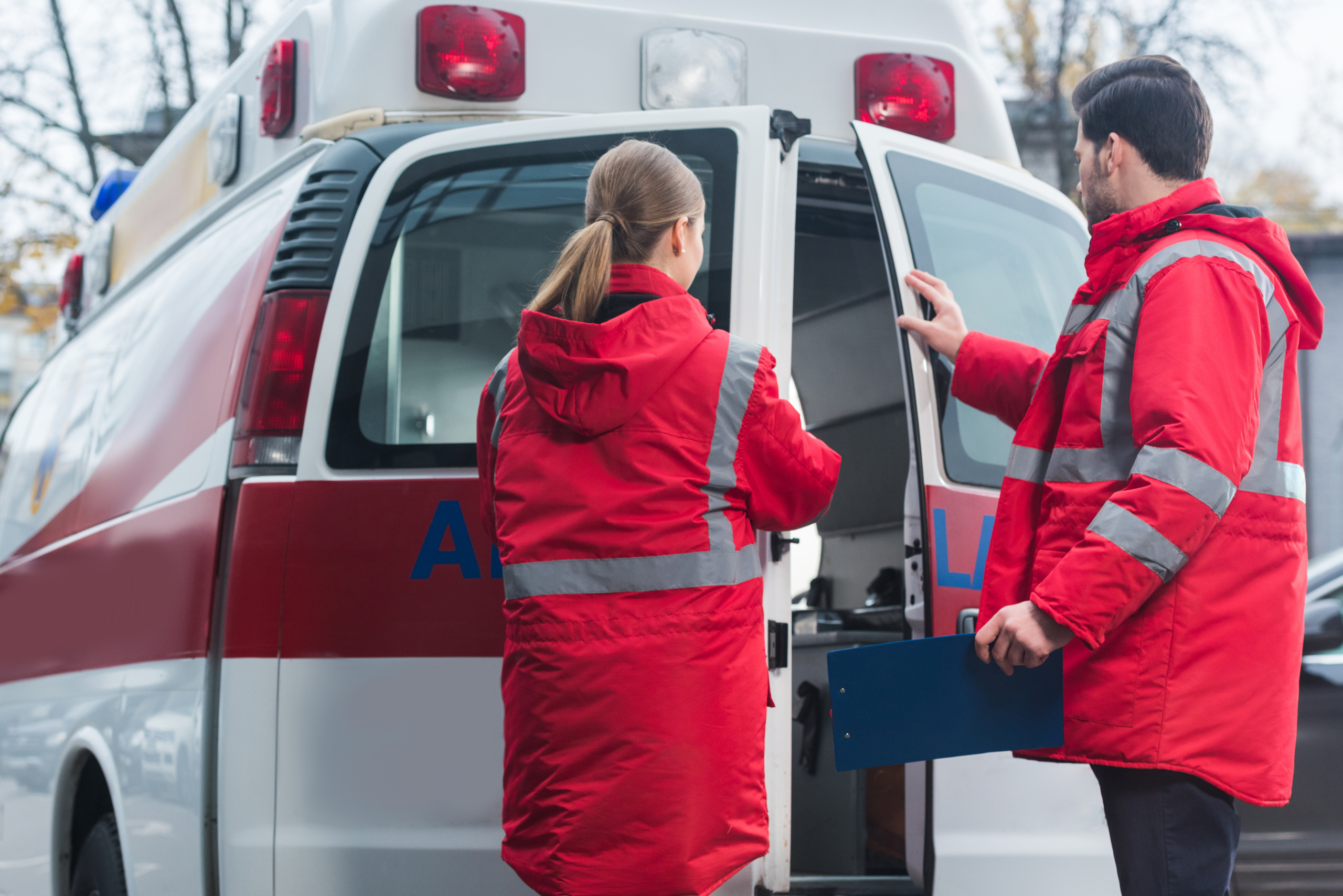 Male and Female emergency response crew close back doors of the ambulance: The WorkTracker healthcare staffing app